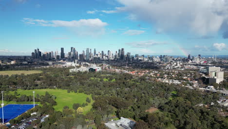 Melbourne-Australia-CBD-from-the-air-view-from-Parkville-on-nice-sunny-day-and-bit-of-cloud-rainbow-in-the-distance-looking-at-Melbourne-Sporting-Complex-Royal-Park-green-parks-and-lot's-of-trees