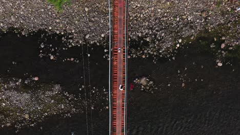 Top-Down-View-Of-People-Crossing-Hanging-Footbridge-In-Guinsaugon,-Southern-Leyte-In-The-Philippines---aerial-drone-shot