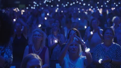Crowd-of-woman-facing-camera,-clapping-their-hands-and-having-fun-at-a-concert
