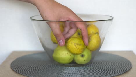 Caucasian-male-picking-up-a-lemon-from-a-fruit-bowl-in-the-kitchen
