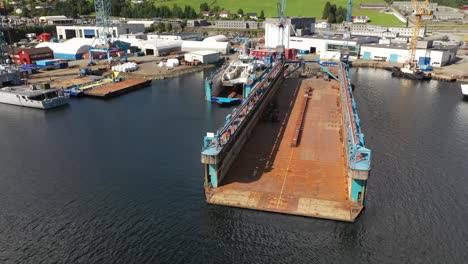 Two-floating-shipyard-drydocks-at-Westcon-yards-Olen-Norway---Beautiful-aerial-view-of-one-massive-empty-dock-and-one-smaller-dock-with-ferryboat-inside