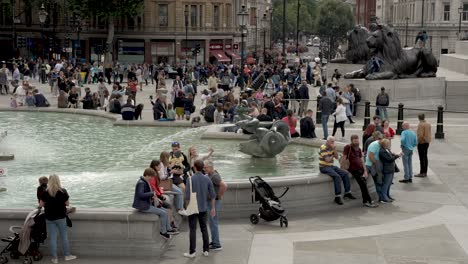 Slow-motion-clip-of-the-trafalgar-quare-in-central-london,-filled-with-crowds-of-people,-a-fountain-and-buildings-in-the-back