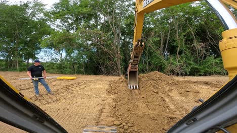 POV-while-operating-a-large-hydraulic-excavator-to-level-bottom-of-overflow-drainage-ditch-at-pond-construction-site