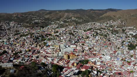 Aerial-drone-rotating-shot-of-Santa-Prisca-Parish-Church-in-the-center-Taxco-de-Alarcon-city-in-Guerrero-state,-Mexico-surrounded-by-mountain-range-at-daytime