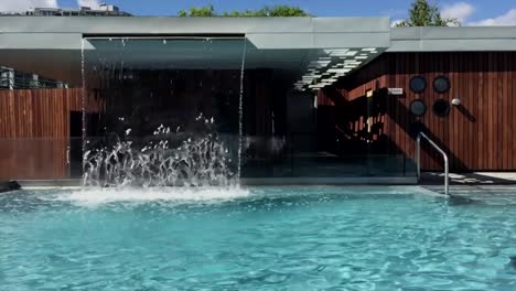 Swimming-pool-with-a-waterfall-flowing-into-it,-slow-motion-video-sequence