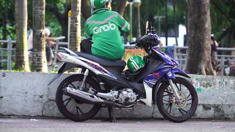 Grab-Rider-Sentado-En-Sus-Motos-Estacionadas-En-La-Calle-De-La-Ciudad-De-Ho-Chi-Minh,-Vietnam