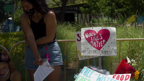 A-Pair-of-BLM-protesters-stand-next-to-Black-Lives-Matter-signs-attached-to-a-fence-in-Downtown