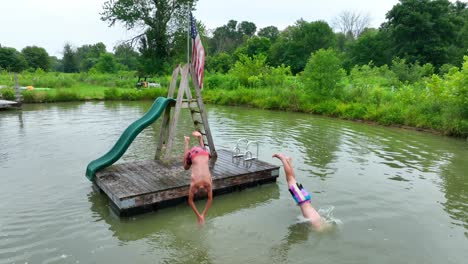 Two-teenage-friends-dive-off-of-dock-at-same-time