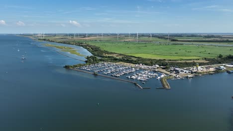 Holländischer-Hafen-Durch-Malerische-Wiesen-Mit-Sich-Drehenden-Windkraftanlagen-Im-Hintergrund