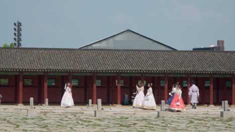 Young-Women-In-Traditional-Hanbok-Dress-Taking-Photos-At-Gyeongbokgung-Palace-Near-The-Throne-Hall-In-Seoul,-South-Korea