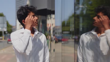 Handsome-young-male-model-fixing-hair-by-looking-in-window-reflection