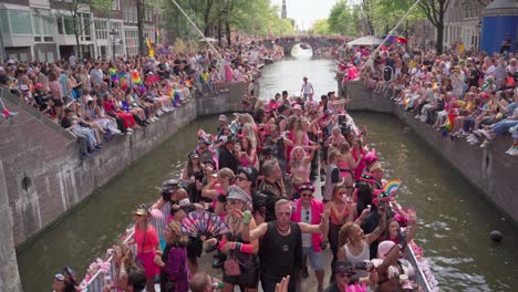 Amsterdam-Canal-Pride-parade-with-people-dancing-on-boat-and-crowds-cheering