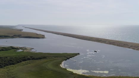 Aerial-tracking-from-left-to-right-with-a-slight-rotation-looking-over-the-fleet-lagoon-at-Abbotsbury,-Dorset