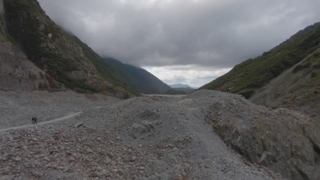 Overview-on-a-rubble-landscape-with-a-river-on-a-very-cloudy-day,-Franz-Josef-Glacier,-New-Zealand