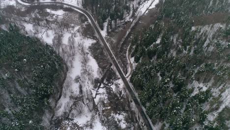 Aerial-view-of-Cars-driving-on-winter-country-road-in-snowy-forest