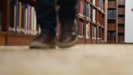 Low-angle-shot-of-a-person's-legs-walking-towards-camera-in-the-library