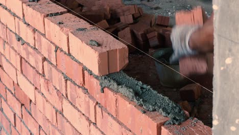 Asian-Man-laying-Bricks-on-top-of-mortar-to-build-wall