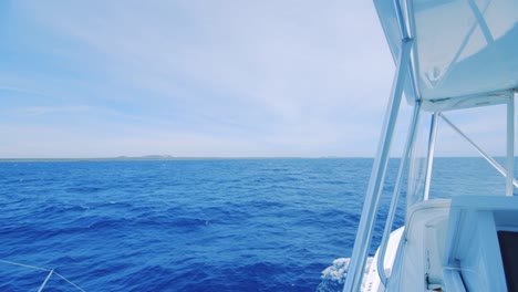 View-of-land-in-distance-beyond-deep-blue-ocean,-seen-from-a-luxury-yacht