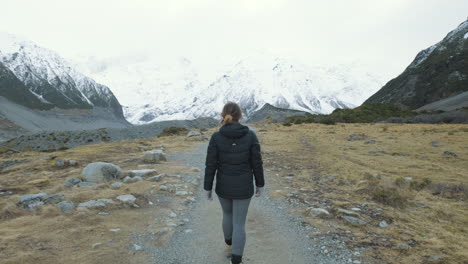 Eine-Folgende-Aufnahme-Einer-Frau,-Die-An-Einem-Kalten-Wintertag-Auf-Der-Südinsel-Von-Neuseeland-Zwischen-Schneebedeckten-Bergen-Spazieren-Geht
