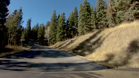 Hyperlapse-drive-down-a-mountain-road-in-autumn-with-a-speed-ramp-slowing-and-then-speeding-up-to-show-the-snowcapped-mountain