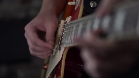 Man-goes-from-strumming-chords-to-picking-individual-notes-on-a-Les-Paul-style-guitar---close-up-side-shot-of-his-strumming-hand