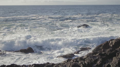 Slow-motion-wide-shot-of-an-ocean-wave-splashing-on-the-rocky-shore