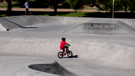 Older-skater-watches-boy-ride-bike-in-the-park
