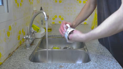 Male-person-washing-a-coffee-mug-at-home