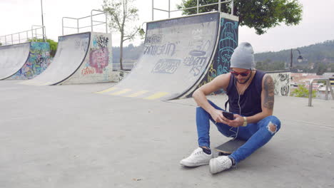 Junge-Mit-Handy-Auf-Einem-Skatepark