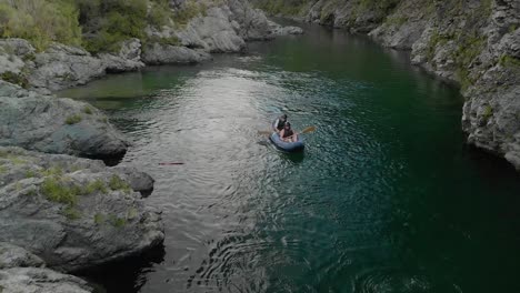 People-on-kayak-tour-paddle-boats-through-canyon-on-Pelorus-river,-New-Zealand-with-native-forrest-and-rock-boulders--Aerial-Drone