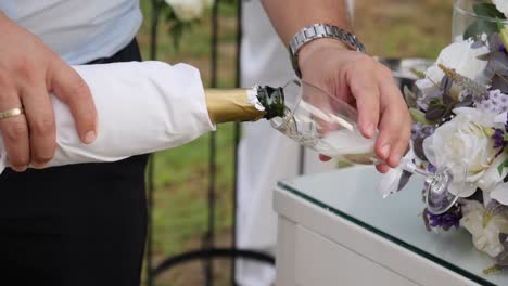 Slow-motion-close-up-of-male-hands-pouring-champagne-outdoors-at-a-wedding-reception-as-pictures-are-being-taken
