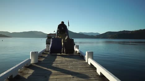 SLOWMO---Male-passenger-with-backpack,-luggage-and-suitcase-boarding-walking-on-dock-and-boarding-boat-in-the-morning-during-sunrise