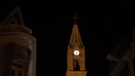 Handheld-shot-of-church-tower-clock-at-night