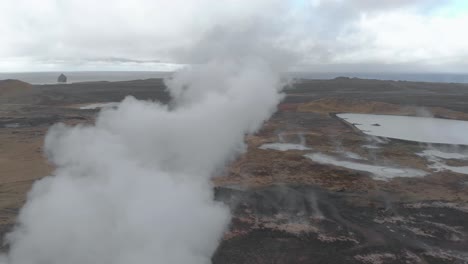 Aerial-panning-shot-of-a-geothermal-hot-spring-billowing-steam-from-the-ground