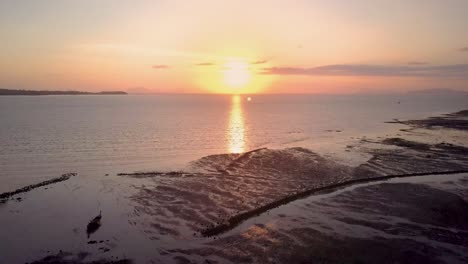 Aerial-view-of-beautiful-ocean-sunset-in-Thailand---camera-tracking-above-water-at-low-tide