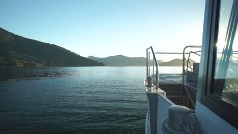 SLOWMO---Morning-sunrise-boat-ride-in-Marlborough-Sounds,-New-Zealand-with-mountains-in-background