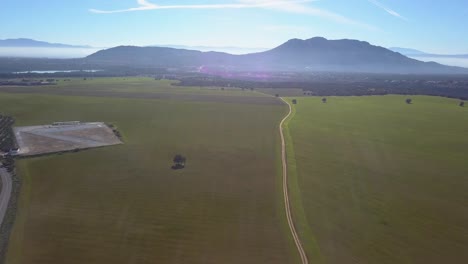 Luftaufnahme-Einer-Ausgedehnten-Wiese-An-Einem-Sonnigen,-Dunstigen-Tag-Mit-Bergen-Im-Hintergrund