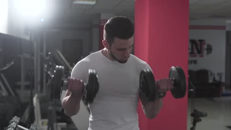 A-fitness-trainer-lifts-two-dumbbells-for-getting-bigger-biceps-and-good-deltoids