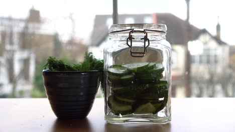 Putting-dill-inside-a-jar-filled-with-cucumber