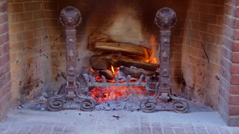 Nahaufnahme-Eines-Holzfeuers,-Das-In-Einem-Alten-Kamin-Mit-Einem-Warmen-Schein-Aus-Kohlen-Und-Asche-Brennt