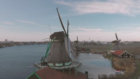 Schwenken-Auf-Eine-Windmühle-Im-Vordergrund-In-Einer-Typischen-Holländischen-Landschaft-Mit-Rotierenden-Dochten-An-Einem-Hellen-Tag-Mit-Blauem-Himmel-Und-Anderen-Windmühlen-Im-Hintergrund