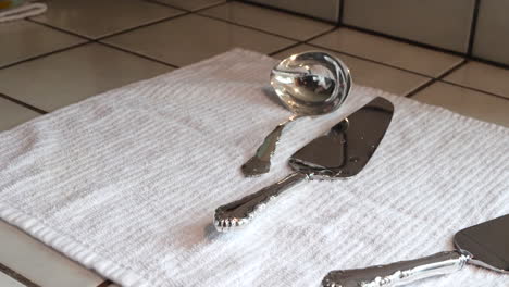 A-woman-drying-off-a-set-of-vintage-silverware-after-cleaning-and-polishing-it-to-remove-tarnish-and-make-it-shiny