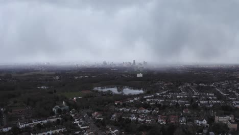 Ariel-shot-of-a-misty-London-City-over-a-small-lake