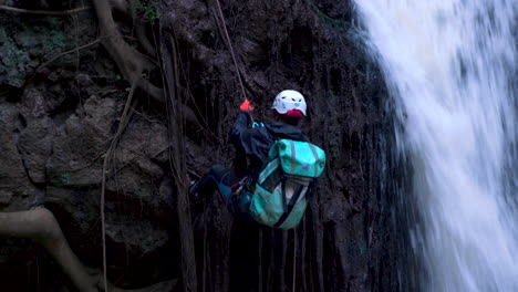 Man-rappelling-down-a-waterfall