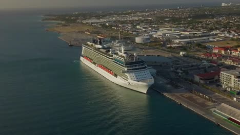 Aerial-overview-of-a-big-cruise-ship-leaving-the-dock-on-a-sunny-day-with-a-slow-zoom-out
