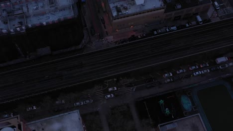 Short-downward-drone-shot-of-rooftops-and-train-tracks-in-Harlem,-New-York-City,-just-after-sunrise,-in-4K