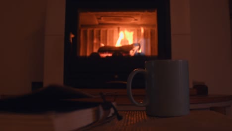 cozy-background-of-a-old-notebook-and-a-cup-with-hot-steam-getting-out-of-it,-near-a-warm-fireplace