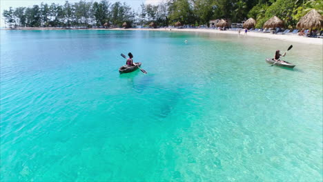 AERIAL:-Slow-motion-girls-kayaking-on-caribbean-beach-resort