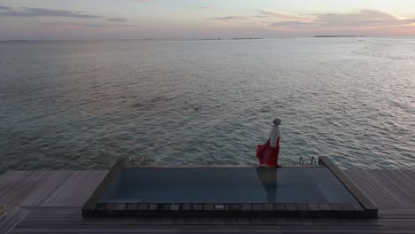 Woman-walks-on-the-edge-of-large-infinity-pool-at-luxury-resort-in-the-Maldives