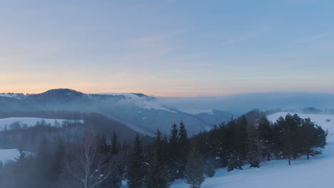 over-a-clouds,-in-front-of-snowy-forrest,-mountain-peaks-and-sunset-colors